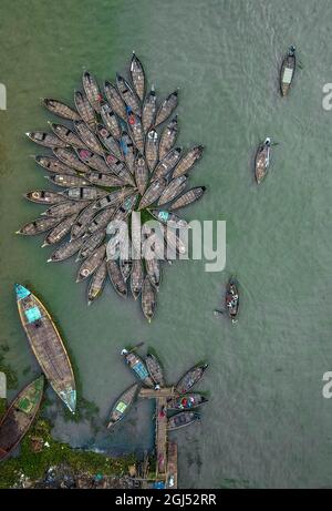 Aus der Vogelperspektive sehen Hunderte von Holzbooten wie Blumen im Buriganga River Port aus. Die mit bunt gemusterten Teppichen geschmückten Boote transportieren Arbeiter aus den Außenbezirken der Stadt zu ihrem Schicksal. Der Buriganga-Fluss wird täglich als Route in die Stadt Dhaka für Millionen von Arbeitern genutzt. Am 9. September 2021 in Dhaka, Bangladesch. (Foto von Mustasinur Rahman Alvi / Eyepix Group) Stockfoto