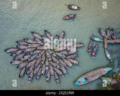 Aus der Vogelperspektive sehen Hunderte von Holzbooten wie Blumen im Buriganga River Port aus. Die mit bunt gemusterten Teppichen geschmückten Boote transportieren Arbeiter aus den Außenbezirken der Stadt zu ihrem Schicksal. Der Buriganga-Fluss wird täglich als Route in die Stadt Dhaka für Millionen von Arbeitern genutzt. Am 9. September 2021 in Dhaka, Bangladesch. (Foto von Mustasinur Rahman Alvi / Eyepix Group) Stockfoto