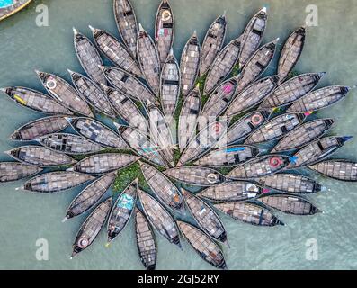 Aus der Vogelperspektive sehen Hunderte von Holzbooten wie Blumen im Buriganga River Port aus. Die mit bunt gemusterten Teppichen geschmückten Boote transportieren Arbeiter aus den Außenbezirken der Stadt zu ihrem Schicksal. Der Buriganga-Fluss wird täglich als Route in die Stadt Dhaka für Millionen von Arbeitern genutzt. Am 9. September 2021 in Dhaka, Bangladesch. (Foto von Mustasinur Rahman Alvi / Eyepix Group) Stockfoto