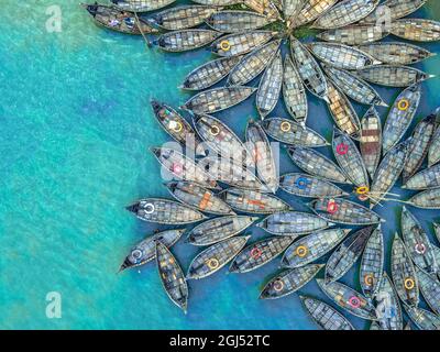 Aus der Vogelperspektive sehen Hunderte von Holzbooten wie Blumen im Buriganga River Port aus. Die mit bunt gemusterten Teppichen geschmückten Boote transportieren Arbeiter aus den Außenbezirken der Stadt zu ihrem Schicksal. Der Buriganga-Fluss wird täglich als Route in die Stadt Dhaka für Millionen von Arbeitern genutzt. Am 9. September 2021 in Dhaka, Bangladesch. (Foto von Mustasinur Rahman Alvi / Eyepix Group) Stockfoto