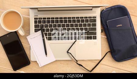 Ein Überblick über Reisedokumente, Gegenstände und Materialien, die auf einem Tisch oder Schreibtisch liegen, von oben. Reisepass, Computer-Laptop, Brille, Notizblock und Stockfoto
