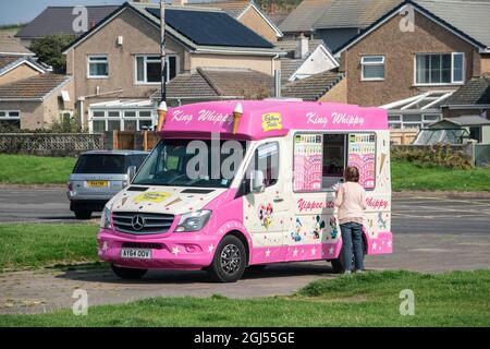 Lady kauft ein Eis aus einem Van, der in der Küstenstadt St. Bees in Cumbria geparkt ist Stockfoto