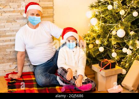 Menschen mit Geschenken tragen Gesichtsmasken während Coronavirus und Grippe Ausbruch an Weihnachten. Schutz vor Viren und Krankheiten, Quarantäne zu Hause. COVID-2019 Stockfoto