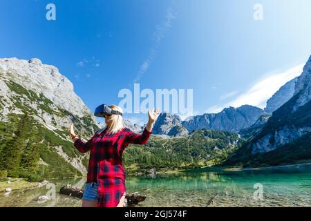 Ein Reisender mit Virtual-Reality-Brille. Das Konzept des virtuellen Reisens um die Welt. Im Hintergrund Schloss Neuschwanstein. Technologie der Zukunft Stockfoto