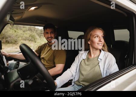 Schönes junges Paar, das auf Beifahrersitzen sitzt und ein Auto fährt Stockfoto