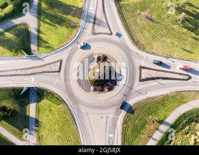 Ein Kreisverkehr aus Drohnensicht. Es gibt ein paar Autos, die ein- und ausfahren. Die Herbstsonne wirft lange Schatten auf die umliegenden Felder. Stockfoto