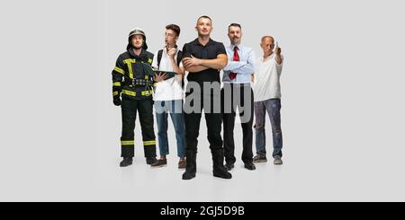 Collage in voller Länge von fünf männlichen Arbeitern verschiedener Berufe in spezieller Uniform, isoliert auf grauem Hintergrund Stockfoto