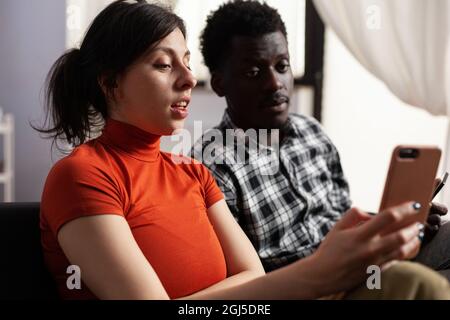 Nahaufnahme von modernen interracial paar mit Smartphones zu Hause. Multiethnische Partner, die digitale Geräte mit Technologie halten. Gemischtes Rennen Menschen mit Gadgets mit Online-Internet. Stockfoto