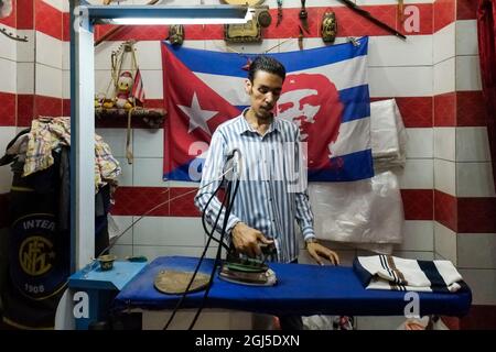 Spaziergang durch den Souk in der Nacht. Mann arbeitet mit Che-Flagge an Bügelkleidung. Assuan, Ägypten. Stockfoto