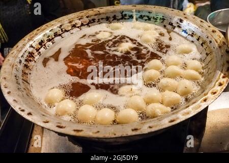 Spaziergang durch den Souk in der Nacht. Anbieter Herstellung gebratener Teig Desserts. Assuan, Ägypten. Stockfoto