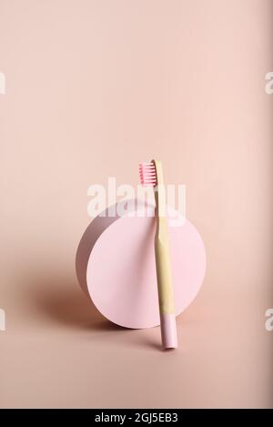Eine umweltfreundliche, rosafarbene Zahnbürste aus natürlichem Bambus in der Nähe des Kreises auf rosa Hintergrund. Gesundheitswesen, Kopierbereich. Zero Waste Konzept. Stockfoto