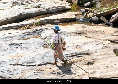 Afrika, Madagaskar, in der Nähe von Andesit, Alaotra-Mangoro-Region. Eine Frau stellt ihre Körbe auf langen Stöcken zusammen, die sie zum Angeln im Fluss verwenden wird. Stockfoto