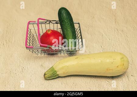 Gemüse in einem kleinen Einkaufskorb: Gurke, Tomaten und Zucchini. Stockfoto