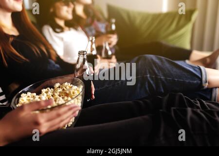 Eine Gruppe von Freunden in 3D-Brillen schaut sich einen Film an, lächelt, lacht. Essen und Trinken, während Sie sich einen Film im Kino ansehen. Mädchen essen Popc Stockfoto