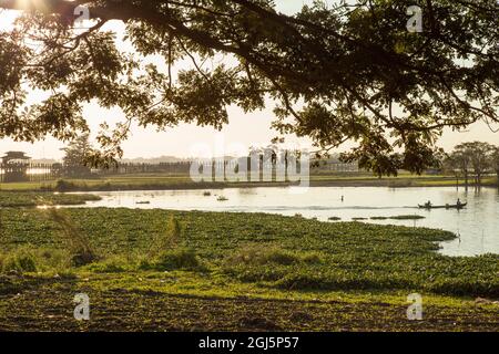 Fischer auf Booten fischen im See in der Nähe von hölzernen Fußgängerbrücke. U Bein Brücke über den Taungthaman See in der Nähe von Amarapura in Mandalay, Myanmar. Stockfoto