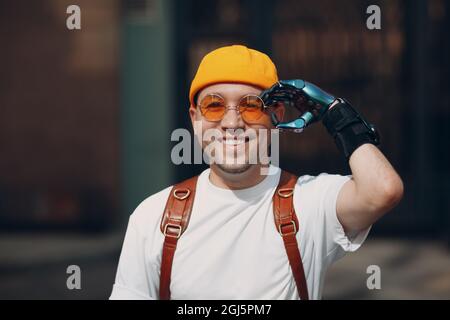 Junge behinderte Mann Porträt auf gelbe Gläser mit künstlichen prothetischen Hand gesetzt Stockfoto