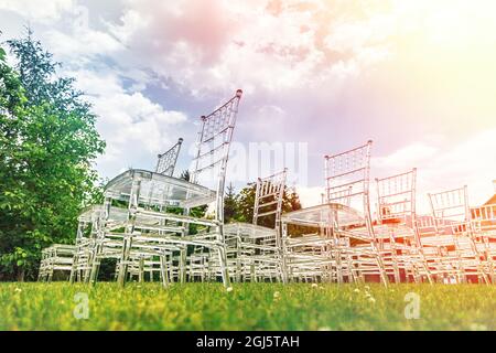 Transparente, elegante und stilvolle Kunststoffstühle. Luxuriöse Einrichtung für die Hochzeitszeremonie im Freien. Stockfoto
