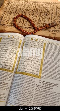 Vertikale Nahaufnahme von Gebetsperlen auf den offenen Seiten des Quran Stockfoto