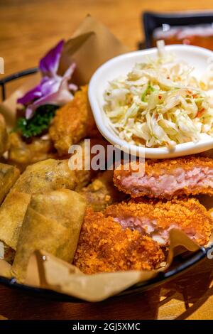 Ein Teller mit thailändischen Snacks, gebratenen Garnelenkuchen, gebratenen Frühlingsrollen und Gemüsesalat Stockfoto