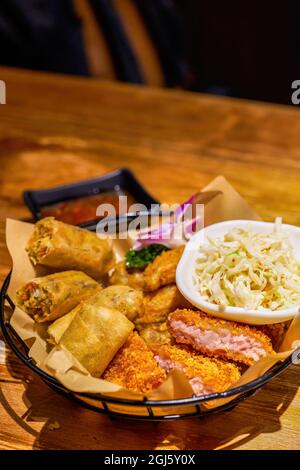 Ein Teller mit thailändischen Snacks, gebratenen Garnelenkuchen, gebratenen Frühlingsrollen und Gemüsesalat Stockfoto