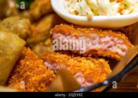 Ein Teller mit thailändischen Snacks, gebratenen Garnelenkuchen, gebratenen Frühlingsrollen und Gemüsesalat Stockfoto