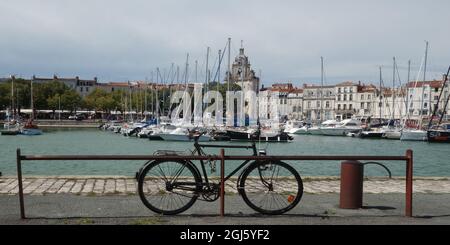 Ein Fahrrad im Hafen mit Yachten vor der Altstadt und dem Uhrenturm, La Rochelle, Biskaya, Frankreich Stockfoto