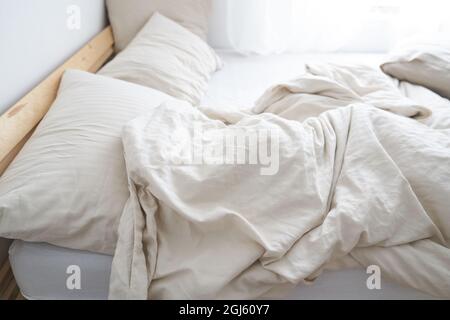 Ein Bett im Innenraum des Zimmers. Das Bett ist nicht gemacht. Beige Farbe. Hochwertige Fotos Stockfoto