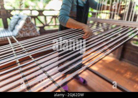 Laos, Vientiane. Lao Textile Museum, Weber arbeitet traditionellen Lao Webstuhl. Stockfoto