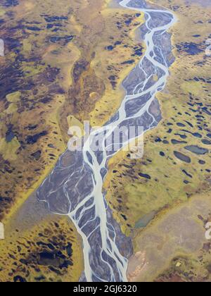 Luftaufnahme eines geflochtenen Flusses auf einer kargen grünen und braunen Landschaft. Stockfoto