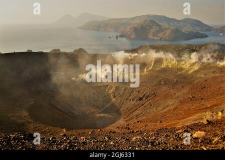 Ein Blick über den Vulkankrater von Vulcano, Italien, mit dampfenden Rumerolen und gelben Schwefelablagerungen. Inseln im Hintergrund, im Mittelmeer Stockfoto