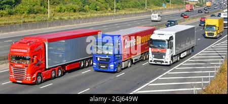 LKW-Marken von Scania man & Mercedes mit Linksverkehr in Großbritannien: EU-registrierte lkw-Lastwagen und Lastwagen überholen die vierspurige Straße in England Stockfoto