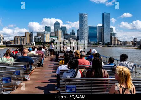 Ein Kreuzfahrtboot auf der Themse nähert sich Canary Wharf, London, Großbritannien. Stockfoto