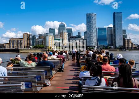 Ein Kreuzfahrtboot auf der Themse nähert sich Canary Wharf, London, Großbritannien. Stockfoto