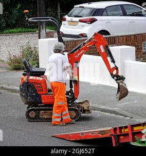 Mini Bagger Bagger auf Mietfahrzeug LKW Fahrer Steuerung Bagger Maschine auf oder aus Fahrzeug Rampe auf Straße Lieferung oder Abholung von Baustelle Großbritannien Stockfoto