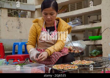 Lokaler Straßenhändler, der vietnamesische Pizza in Sapa, Vietnam, macht. Stockfoto