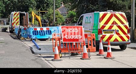 Red Road Work geschlossen Schild Barrieren für Wassertafel Auftragnehmer Lieferwagen und Ausrüstung, um eine berstende Wasserleitung in Beton Wohnstraße England Großbritannien zu beheben Stockfoto