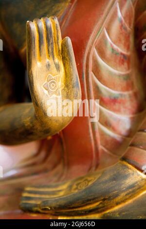 Kambodscha, Siem Reap, goldene Hände auf roter Holzstatue des Buddha. Stockfoto