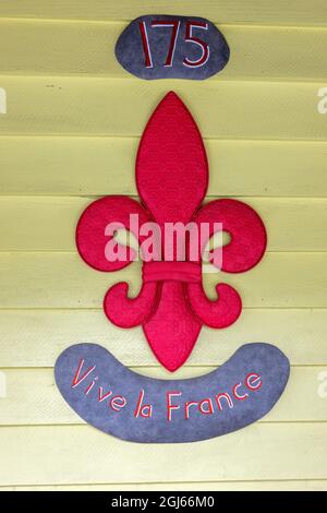 Rotes gestepptes Stofffleur-de-Lis Vive la France Schild vor Einem Gebäude in Akaroa, Neuseeland Stockfoto