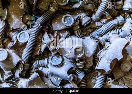 Ukraine, Pripjat, Tschernobyl. Gasmasken, viele davon kindergroß, fallen auf den Boden einer verlassenen Schule. Stockfoto