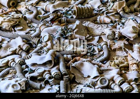 Ukraine, Pripjat, Tschernobyl. Gasmasken, viele davon kindergroß, fallen auf den Boden einer verlassenen Schule. Stockfoto