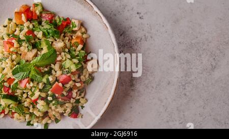 Panoramablick auf Tabbouleh-Salat. Traditionelles nahöstliches oder arabisches Gericht mit Petersilie, Minze, Bulgur und Tomaten in einer Schüssel auf hellem Hintergrund. Draufsicht. Speicherplatz kopieren Stockfoto