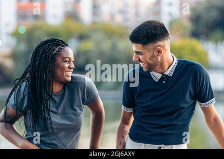 Zwei junge Menschen unterschiedlicher Ethnien lachen im Sommer in einem Park Stockfoto