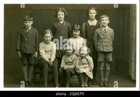 Original sehr klares Bild von Studio-Portrait-Postkarte aus den 30er Jahren von 8 Kindern, Geschwistern oder Cousins, Schuluniformen, Lincoln, England, Großbritannien um 1935 Stockfoto