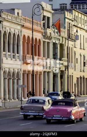 Kuba, Havanna. Klassische Automobile fahren auf Malecon an historischer Architektur vorbei. Havanna Vieja (Alt-Havanna) ist ein UNESCO-Weltkulturerbe. Stockfoto