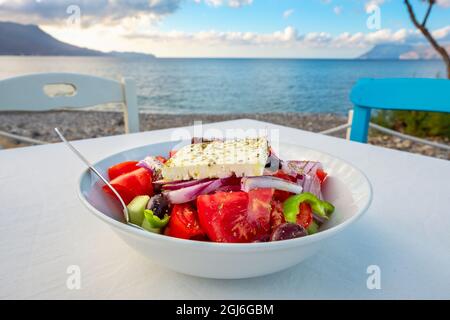 Traditioneller griechischer Salat auf einem Tisch in der Taverne am Meer in Kissamos. Kreta, Griechenland Stockfoto