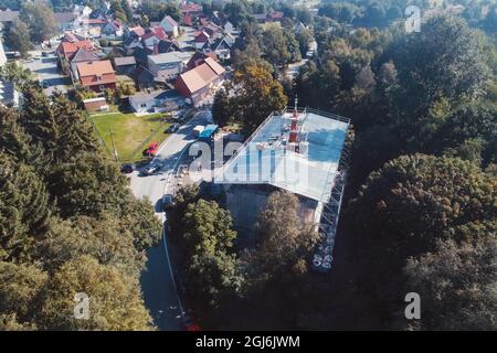 Stiege, Deutschland. September 2021. Handwerker platzieren die Turmdekoration auf der Stabkirche. Die Holzkirche im norwegischen Drachenstil, die in Deutschland einzigartig ist, wurde aus dem Wald im Harz nach Stiege verlegt. In wenigen Wochen sollten der Umzug und der Wiederaufbau abgeschlossen sein. Quelle: Matthias Bein/dpa-Zentralbild/ZB/dpa/Alamy Live News Stockfoto