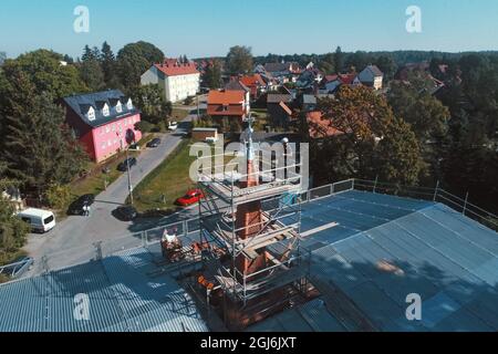 Stiege, Deutschland. September 2021. Handwerker platzieren die Turmdekoration auf der Stabkirche. Die Holzkirche im norwegischen Drachenstil, die in Deutschland einzigartig ist, wurde aus dem Wald im Harz nach Stiege verlegt. In wenigen Wochen sollten der Umzug und der Wiederaufbau abgeschlossen sein. Quelle: Matthias Bein/dpa-Zentralbild/ZB/dpa/Alamy Live News Stockfoto