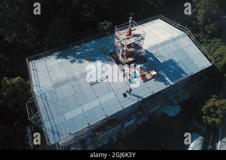 Stiege, Deutschland. September 2021. Handwerker platzieren die Turmdekoration auf der Stabkirche. Die Holzkirche im norwegischen Drachenstil, die in Deutschland einzigartig ist, wurde aus dem Wald im Harz nach Stiege verlegt. In wenigen Wochen sollten der Umzug und der Wiederaufbau abgeschlossen sein. Quelle: Matthias Bein/dpa-Zentralbild/ZB/dpa/Alamy Live News Stockfoto