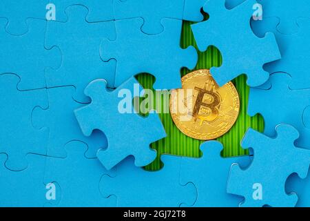 Blaues Puzzle mit goldenem Bitcoin darunter Stockfoto