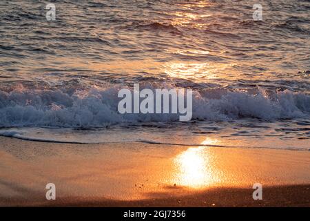 Wellen krachen am schwarzen Sandstrand von Santorini, Griechenland. Stockfoto